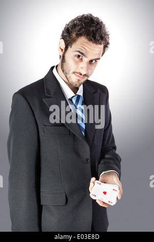 Un elegante giovane imprenditore che mostra un asso di cuori in mano Foto Stock