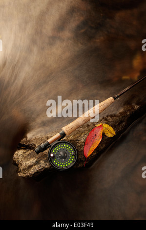 Canna da pesca a mosca in appoggio su di una roccia in un torrente durante l'autunno Foto Stock