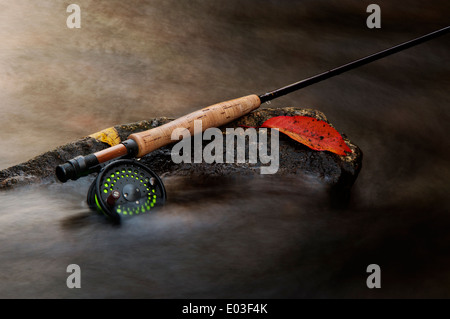 Canna da pesca a mosca in appoggio su di una roccia in un torrente durante l'autunno Foto Stock