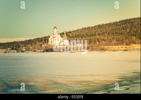 I cristiani ortodossi Chiesa tempio sul lago ghiacciato con foresta montagne sullo sfondo lo splendido paesaggio Foto Stock