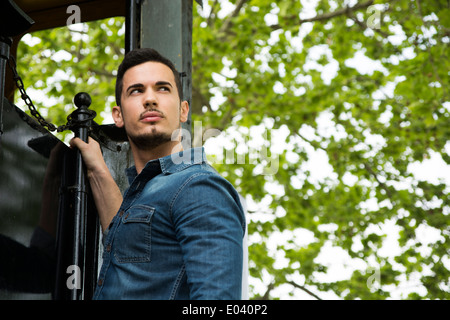 Bel giovane uomo in denim shirt appeso dal vecchio treno girato dal di sotto Foto Stock