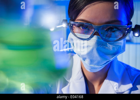Un Cinese Asian femmina o medico ricercatore scientifico o medico guardando un pallone di liquido verde in un laboratorio. Foto Stock