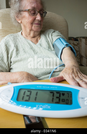 Signora anziana nei suoi anni novanta avente la pressione sanguigna ckecked a casa Foto Stock