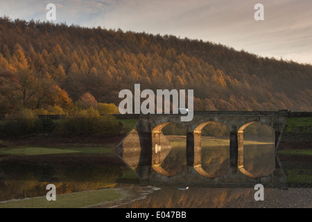 Vista panoramica del soleggiato archi del ponte stradale & woodland, riflesso in acque calme di Lindley serbatoio di legno - vicino a Otley, North Yorkshire, Inghilterra, Regno Unito. Foto Stock