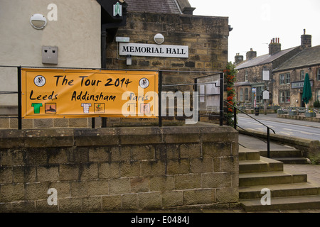Orange banner su railingss fuori dal villaggio HALL, collocati lungo il percorso del Tour de France accoglie i visitatori a Addingham - West Yorkshire, Inghilterra, Regno Unito. Foto Stock