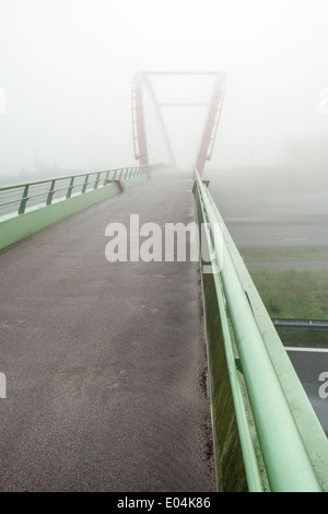 Questo ponte è sotto una fitta nebbia la mattina del giorno Foto Stock