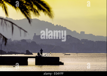 L'Europa, Francia, Alpes-Maritimes, Cannes. Fisherman davanti alla città vecchia al tramonto. Foto Stock