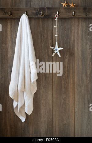 Asciugamano bianco appeso alla parete del bagno con decorazione di stelle marine Foto Stock