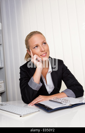 Un giovane imprenditrice di successo si siede alla sua scrivania in ufficio, Eine junge, erfolgreiche Geschaeftsfrau sitzt un ihrem Schreib Foto Stock