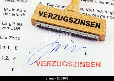 Un francobollo di legno si trova su un documento. Etichetta tedesca: gli interessi di mora, Ein Stempel aus Holz liegt auf einem Dokument. Deutsche Foto Stock