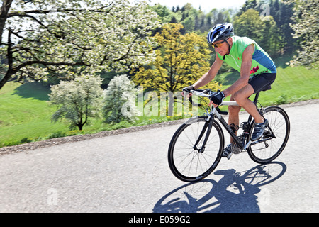 Boss allenatori fitness e rigidi bicicletta su una ruota da corsa, Senior Fitness trainiert und faehrt Fahrrad auf einem Rennrad Foto Stock