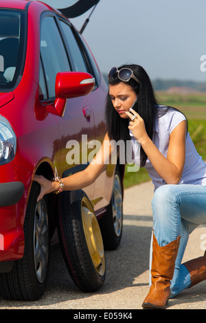 Giovane donna con un maturo di rottura con la vettura, Junge Frau mit einer Reifen Panne beim Auto Foto Stock