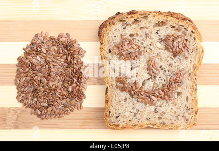 Primo piano di semi di lino sul tagliere con fette di pane integrale Foto Stock