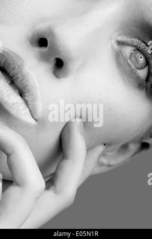 Bianco e nero ritagliate ritratto di bellezza di close-up di un giovane volto di donna con dita toccano la sua guancia Foto Stock