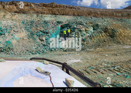 Due geologi ispezionare un affioramento di roccia contenente un sacco di minerale di rame in un massiccio a cielo aperto di rame e di miniera d'oro Foto Stock