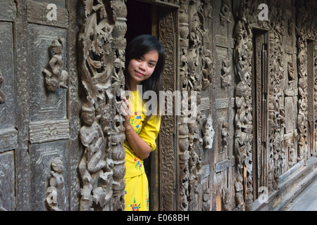 Ragazza dalla porta di legno nel monastero Shwenandaw, noto anche come l'ex Palazzo Reale fatta di legno, Mandalay Myanmar Foto Stock