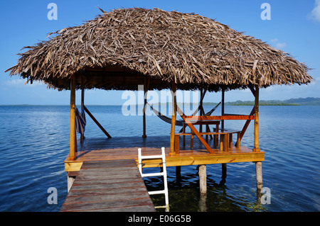 Rifugio tropicale su palafitte sopra l'acqua con tetto di paglia fatta di secche foglie di palma, Mar dei Caraibi Foto Stock