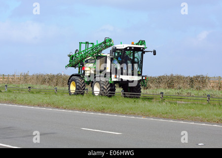 Un raccolto macchina di spruzzatura che viaggiano lungo la A417 a doppia carreggiata in Cotswolds, Inghilterra Foto Stock