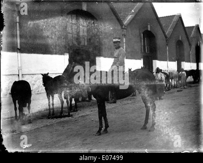 Questo dipinto mostra un ufficiale in uniforme a cavallo di fronte alle scuderie. L'ufficiale militare è raffigurato in un abbigliamento formale, con una forte enfasi sui dettagli uniformi e sulla posizione del cavallo, mettendo in risalto la cultura militare e le tradizioni equestri dell'epoca. Foto Stock