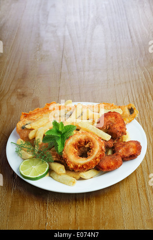 Piatto di frutti di mare con pesce impanati,calamari,di gamberi e potato chips sul tavolo vintage Foto Stock