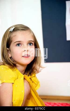 Ragazza indossando maglietta gialla e clip per capelli, ritratto Foto Stock