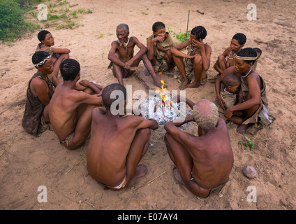 Boscimane di persone attorno a un fuoco in un villaggio tradizionale, Tsumkwe, Namibia Foto Stock