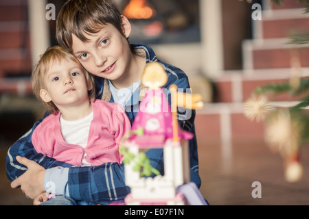 Fratello e Sorella guardando presenta sotto albero di Natale Foto Stock