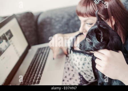 Giovane donna utilizzando laptop assieme al suo cane Foto Stock