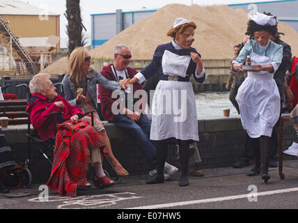 1940s ostetriche su chiamata dal teatro Vamos arrivano nella loro divise, spingendo il loro carrello e aiutando gli ignari membri del pubblico come parte di Poole Street Arts Festival sulla banchina per celebrare il giorno di maggio Banca Credito Vacanze: Carolyn Jenkins/Alamy Live News Foto Stock