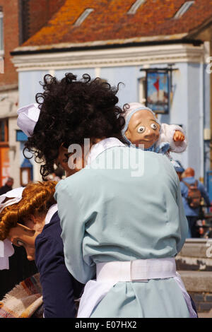 1940s ostetriche su chiamata dal teatro Vamos arrivano nella loro divise, spingendo il loro carrello e aiutando gli ignari membri del pubblico come parte di Poole Street Arts Festival sulla banchina per celebrare il giorno di maggio Banca Credito Vacanze: Carolyn Jenkins/Alamy Live News Foto Stock