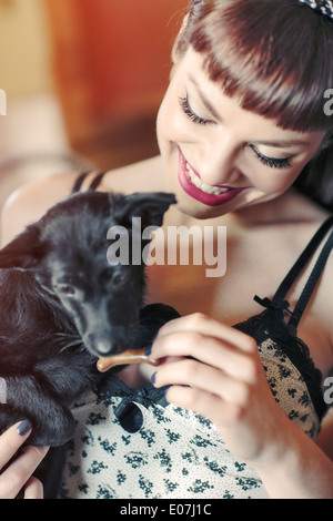 Giovane donna alimentazione cane con biscotti Foto Stock