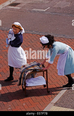 1940s ostetriche su chiamata dal teatro Vamos arrivano nella loro divise, spingendo il loro carrello e aiutando gli ignari membri del pubblico come parte di Poole Street Arts Festival sulla banchina per celebrare il giorno di maggio Banca Credito Vacanze: Carolyn Jenkins/Alamy Live News Foto Stock