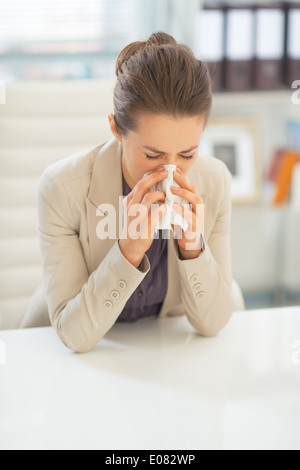 Business Woman in ufficio il naso di soffiatura Foto Stock