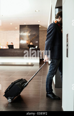 Imprenditore con bagagli entrando in ascensore in hotel Foto Stock