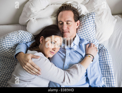 Elevato angolo di visione della donna triste che comprenda l'uomo mentre giaceva a letto Foto Stock
