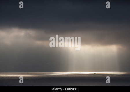 La luminosa luce del sole passa attraverso il buio e nuvole temporalesche. Baia di Tangeri, Marocco Foto Stock