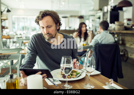 Uomo maturo con tavoletta digitale nel ristorante Foto Stock