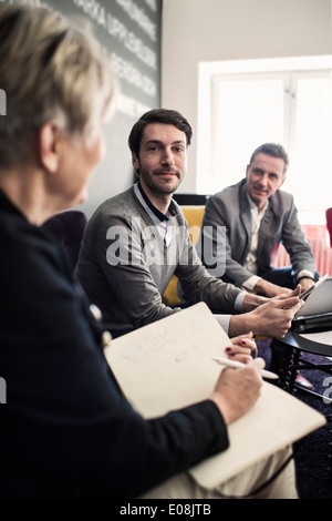 Ritratto di imprenditore fiducioso seduta con i colleghi presso la lobby. Foto Stock