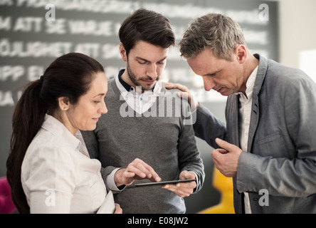 Colleghi di lavoro utilizzando tavoletta digitale presso la lobby di office Foto Stock