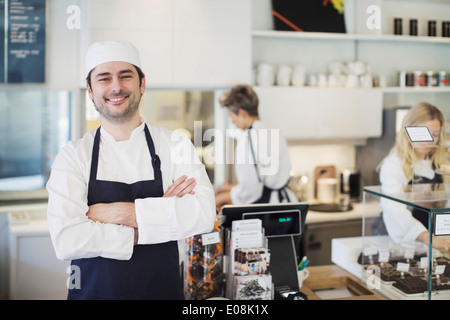 Ritratto di fiducioso proprietario in piedi con le braccia incrociate in cafe Foto Stock