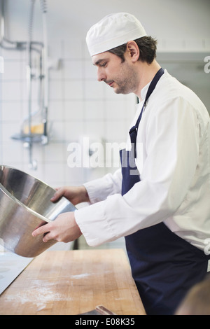 Vista laterale del panettiere del maschio che lavorano in cucina commerciale Foto Stock