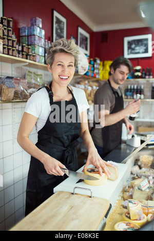 Ritratto di felice commessa formaggio da taglio a contatore nel supermercato Foto Stock