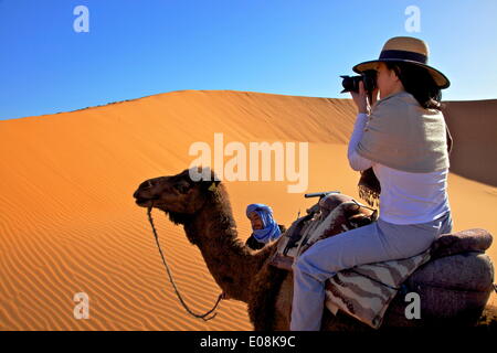 Tourist sul cammello tenendo fotografia, con uomo berbero, Marocco, Africa Settentrionale, Africa Foto Stock