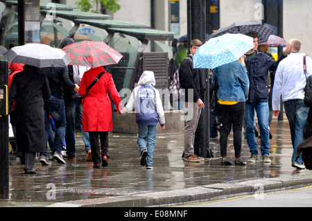 Londra, Inghilterra, Regno Unito. La gente camminare sotto la pioggia con ombrelloni Foto Stock