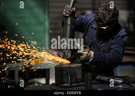 Operaio di fabbrica utilizzando smerigliatrice angolare per il taglio di metalli Foto Stock