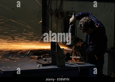 Operaio di fabbrica utilizzando smerigliatrice angolare per il taglio di metalli Foto Stock