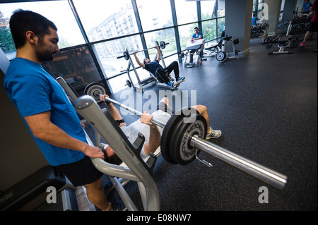 L'uomo sollevamento pesi nella palestra con l aiuto di uno spotter Foto Stock