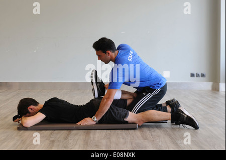 Personal trainer in palestra per aiutare il cliente a fare esercizi di stretching Foto Stock