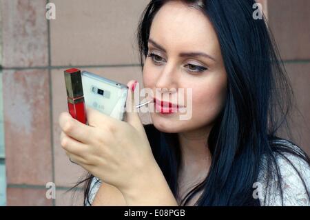 Illustrazione - un'immagine illustrata mostra una donna che applica il make-up e utilizza il suo telefono cellulare come specchio. Fotoarchiv für Zeitgeschichte ATTENZIONE! NESSUN MODELLO DI SERVIZIO DI CABLAGGIO RILASCIATO Foto Stock