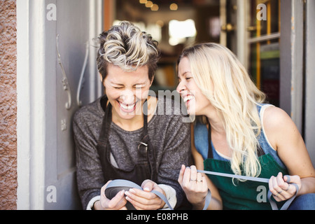 Felice designer di moda con bobina di nastro seduto alla porta studio Foto Stock